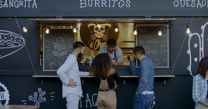 Cheerful waiter taking order from multi-racial customers at counter, Mexican street food served from a food truck. 4K UHD RAW graded footage