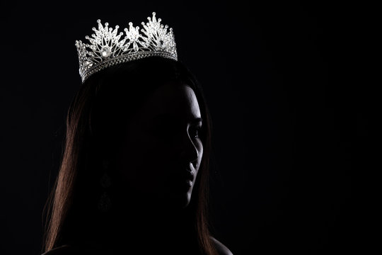 Portrait of Miss Pageant Beauty Contest in sequin Evening Ball Gown long dress with sparkle light Diamond Crown, silhouette low key exposure with curtain, studio lighting dark background dramatic