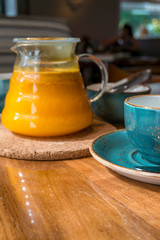 Sea buckthorn tea infusion in glass teapot with teal cup