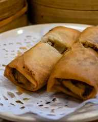 Spring rolls in a plate in front of bamboo steamers