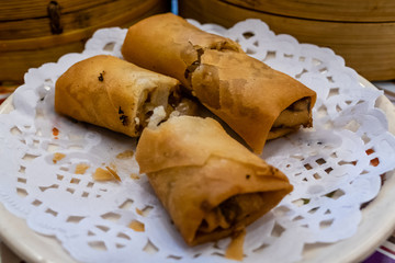 Spring rolls in a plate in front of bamboo steamers