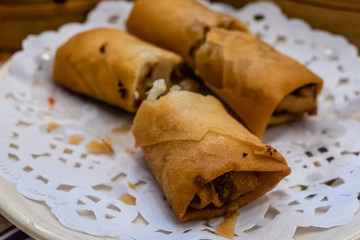 Spring rolls in a plate in front of bamboo steamers