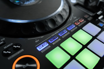 Fototapeta premium Close up DJ mixer player and sound console for house music party. DJ controller for mixing music and colorful light in nightclub. Disc jockey panel and mixing deck at dance party