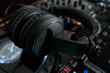 Fototapeta na wymiar Professional dj headphones on audio mixer controller.Big black headset on sound mixing panel.Audio equipment for disc jockey