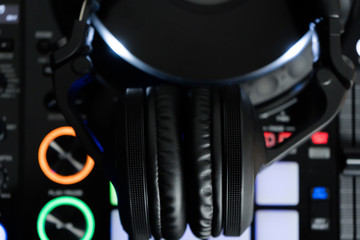Obraz na płótnie Canvas Professional dj headphones on audio mixer controller.Big black headset on sound mixing panel.Audio equipment for disc jockey