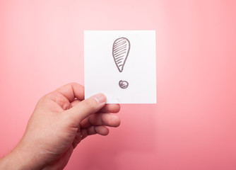 hand holding sticker with exclamation mark isolated on pink background