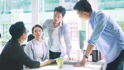 group of four young asian business people men and woman meeting discussing in office