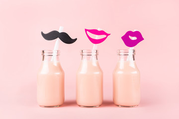 Three bottles of drink on pink background.