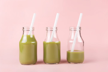 Three bottles with colorful drinks on pink background.