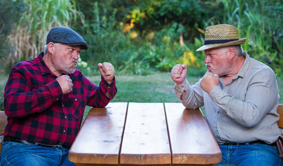 Two older men are sitting at a table discussing and arguing. Concept: quarrel and aggression