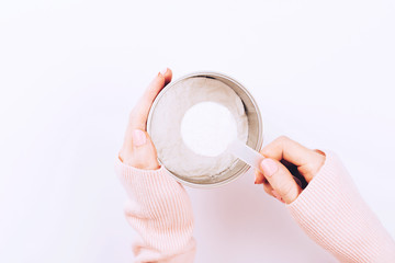 A jar with collagen powder and scoop spoon in woman hands.