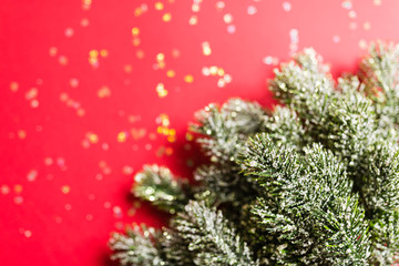 Christmas tree branches on red background with golden confetti. new year concept. Greeting card, xmas celebration 2020. Flat lay, top view, copy space, mockup