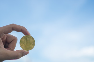 Plakat Hand hold a symbol of Bitcoins as cryptocurrency with nature background with copyspace that you can put text on.