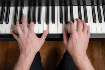 Close up of a man playing the piano. Left hand plays a Power Chord and right hand plays the melody.