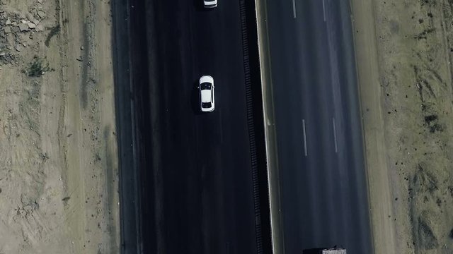 A slow mo aerial top view of a heavy trawler and two white cars moving on a highway in northern areas.