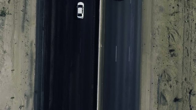 A slow mo aerial top view of two cars moving on a highway in northern areas.
