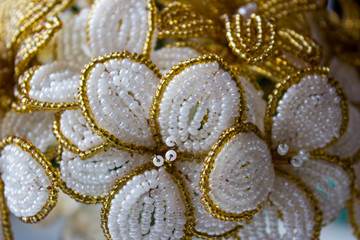 Bouquet of beaded flowers, white and gold flowers. Macro view from the side.