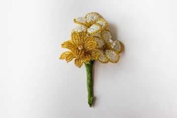 A beaded flower in the center on a white background. Golden flowers on a light background. Beads on a white background.