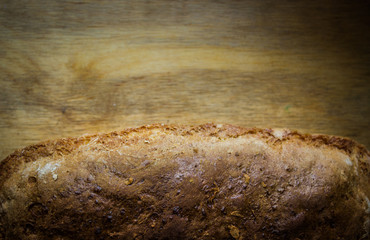 Bread with a crust at the bottom of the background. Bread on a wooden background close-up. View from above.