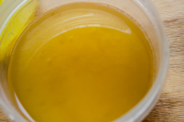 Honey in a jar on a wooden yellow table. Honey close-up. View from above.