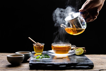 Healthy hot tea with hot steam, honey water and a cup of beautifully placed tea. - Healthy herbal water concept