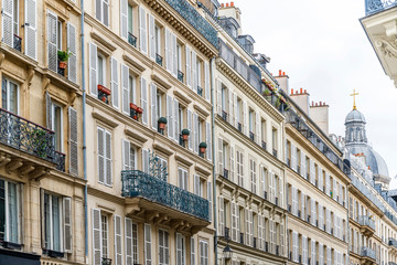 Quarter of high-rise residential buildings with balconies and shutters and the dome of Christian church in Paris