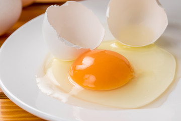 木の背景に白いお皿に生卵が乗っているコピースペース、朝食、料理用