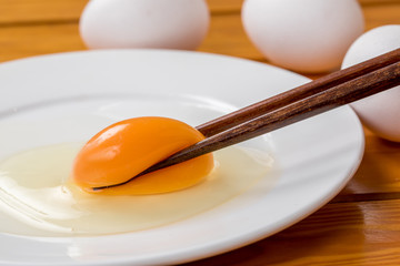箸で持ち上げた生卵の黄身