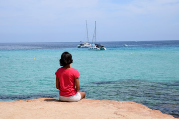 Joven mujer sentada en la costa de Ibiza