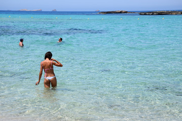 Hermosa mujer entrando a bañarse a las aguas turquezas de Ibiza