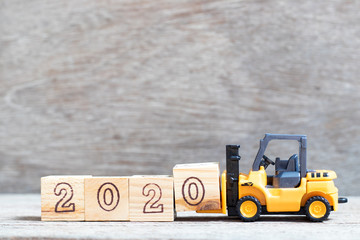 Toy forklift hold letter block 0 in word 2020 on wood background
