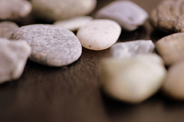Fototapeta na wymiar Scattered pebble stones on a dark background close up