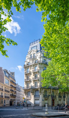 Street with storey residential buildings and green trees in Paris