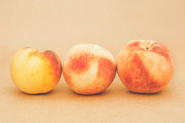 Bright fresh peaches on a yellow beige background. Sweet juicy peaches. Close.