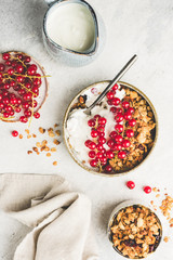 Healthy breakfast food oat granola with milk and berries on white concrete background. Table top view