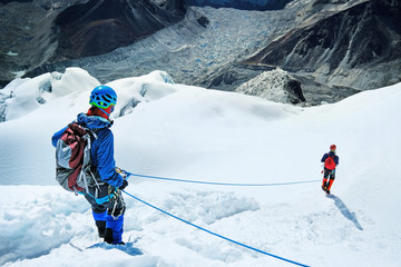 Climber reaches the summit of mountain peak enjoying the landscape view.