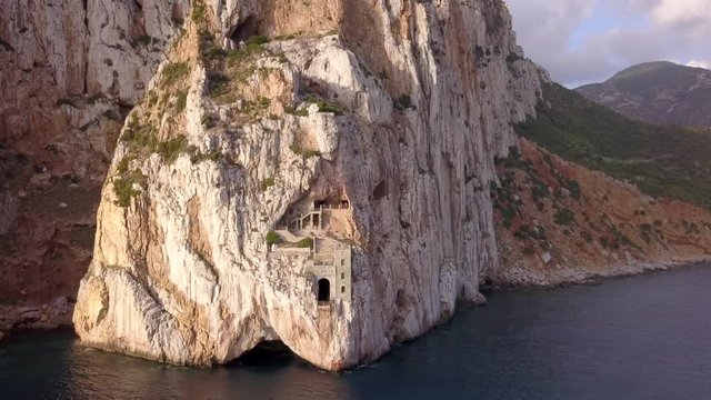 Drone shot of Porto Flavia an abandoned mineral storage pier in the coast of Sardinia in Italy.The shot is moving towards the left.