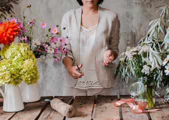 Female professional florist prepares the arrangement of wild flowers.