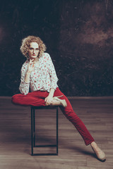 A young blond man androgyn in the image of an attractive woman  dressed in a floral shirt, posing...