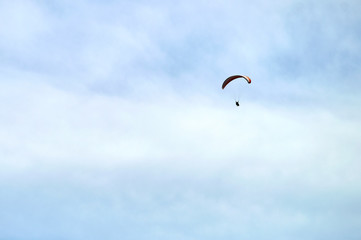 skydiver gliding in the clouds on yellow and blue wing