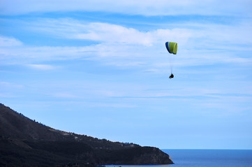 parachutist flying above the ocean and mountains