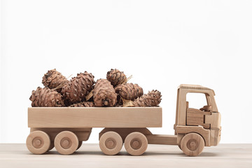  Lot of pine cones in back of  toy car made of wood.