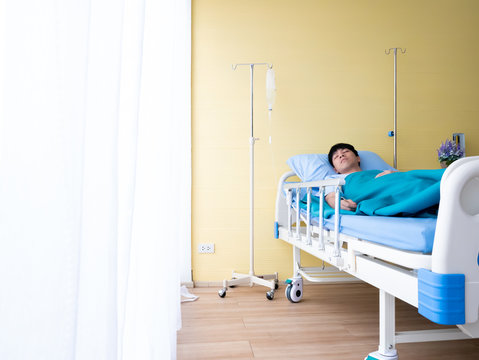 20s 30s Asian Patient Young Man Asleep On Bed For Recovery Body From Illness Symptom In Yellow VIP Emergency Room Hospital And Beautiful Flower From Caregiver And Visitor With White Curtain Copy Space