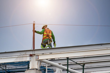 Naklejka na ściany i meble Man working on construction site with scaffold and building with sky background,scaffolding for construction factory