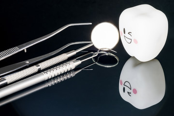 Close up; Dental tools and smile teeth model on black background.