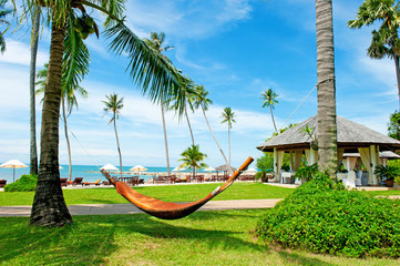 Tropical Beach Resort. Empty hammock between palm trees on tropical beach. Paradise Island for holidays and relaxation.