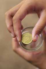 Hand holding coin saving money.