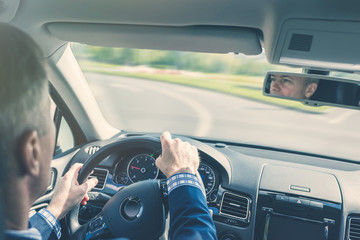 Selective focus of elderly man hands on steering wheel driving a car on the speed highway. View...