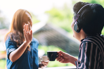 A man greeting and say hi to his female friend while enjoy listening to music with headphone and drinking coffee