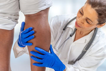 phlebologist inspecting a woman's leg looking for varicose veins on white background